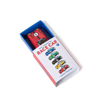 A miniature vintage race car toy in an open blue and white presentation box, photographed on a clean white background.